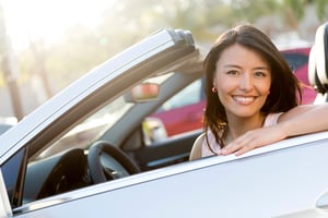 Beautiful female driver in a convertible car smiling