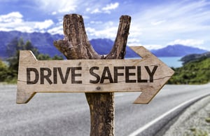 Drive Safely wooden sign with a street background