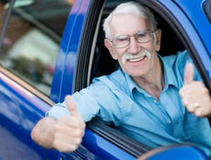 Man driving a car and showing thumbs up